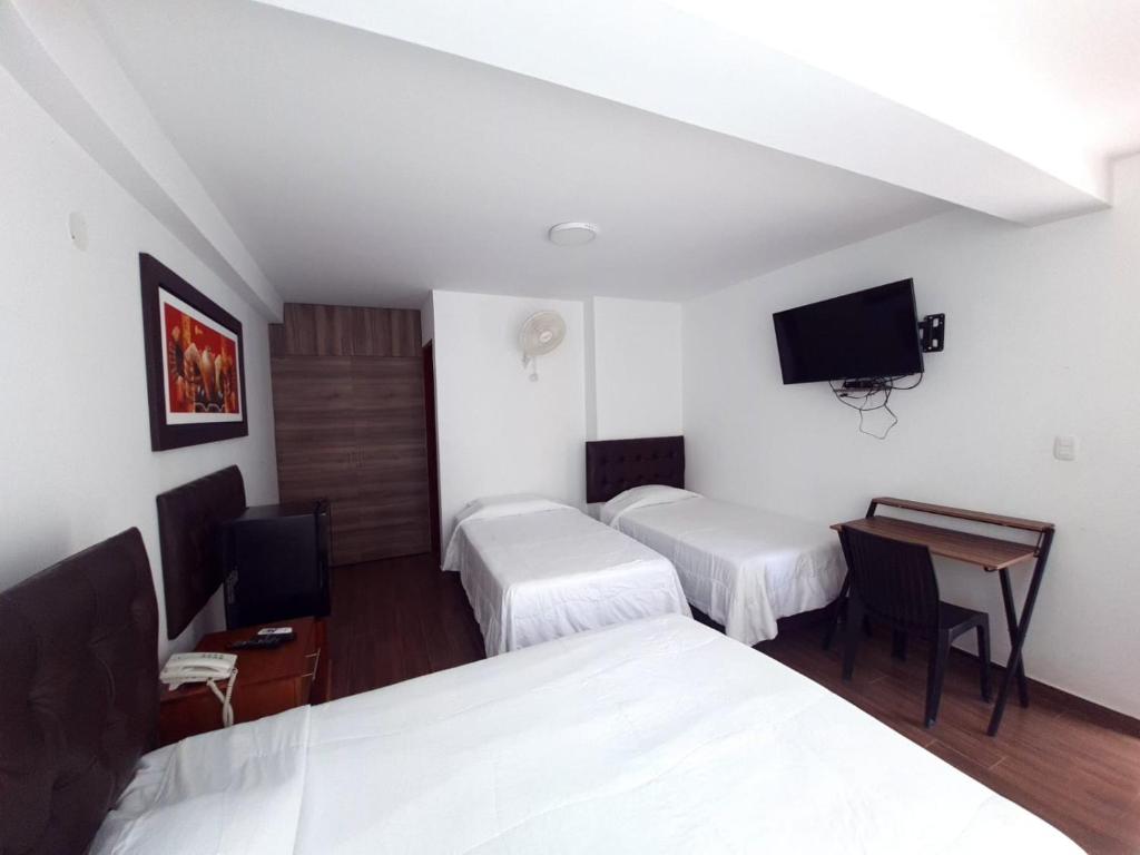 帕拉卡斯Hotel Golf Paracas的客房设有两张床、一张桌子和一台电视机。