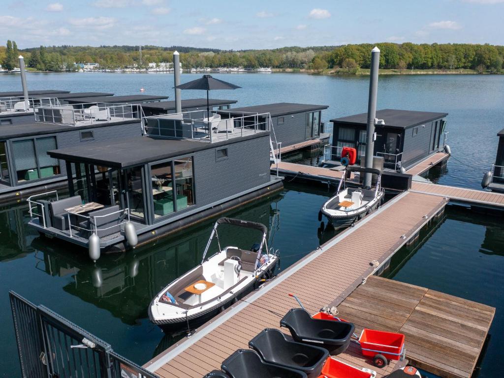 MiddelaarLuxury houseboat with roof terrace and beautiful view over the Mookerplas的两艘船停靠在湖上的一个码头