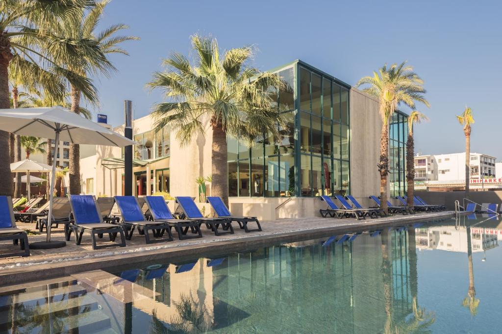 圣安东尼奥湾伊维萨西方酒店的一个带蓝色躺椅的游泳池,棕榈树