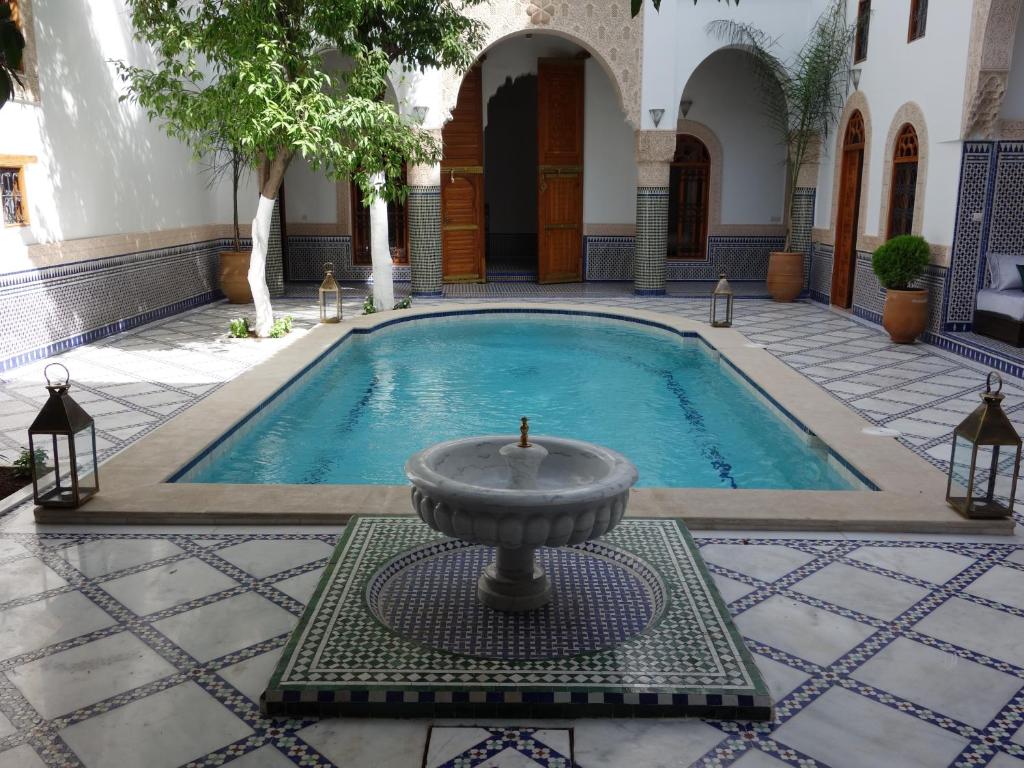 非斯里亚德沙巴酒店的一座建筑中间的游泳池,有一个喷泉