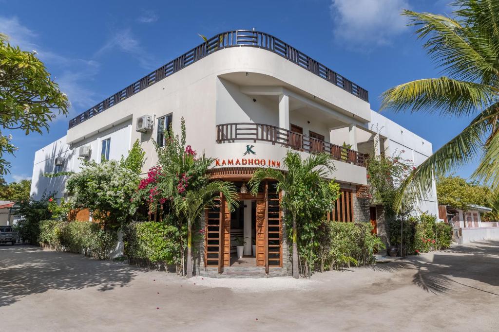 芭环礁Kamadhoo Inn的带阳台和棕榈树的白色建筑