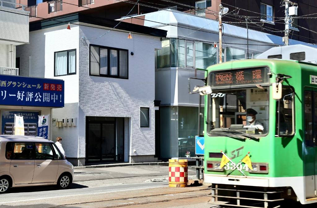 札幌Dream Tree 札幌市电步行0分钟 超市步行1分钟的一辆绿色的巴士沿着大楼旁边的街道行驶
