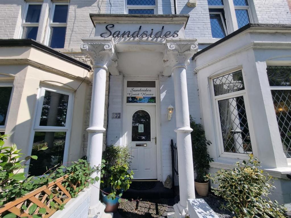 惠特利湾Sandsides Guest House的一间白色的房子,上面标有读三明治的标志