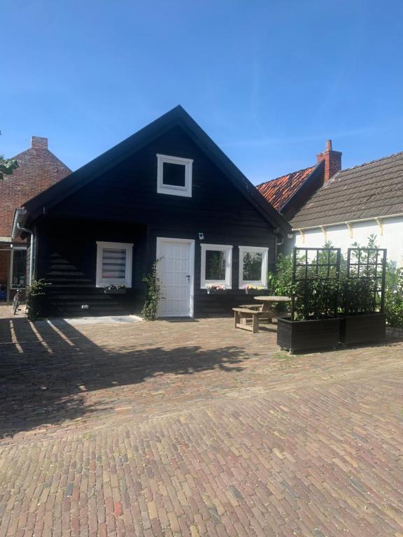 WinsumHet molenhuisje的黑白房子前面有长凳