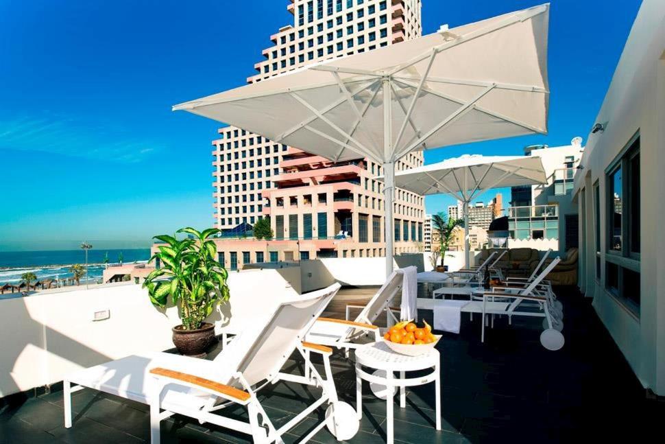 特拉维夫贝尔Spa精品酒店的阳台配有白色的桌椅和遮阳伞。