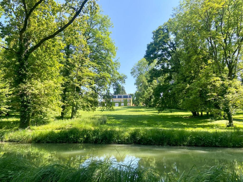Château de Belleaucourt的树木和草地公园里的池塘