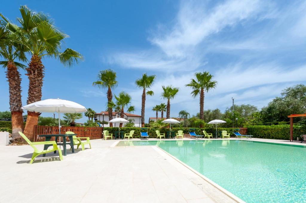 卡斯泰诺福奇伦托Residence Martino - Casa Vacanze的一个带椅子和遮阳伞的游泳池以及棕榈树