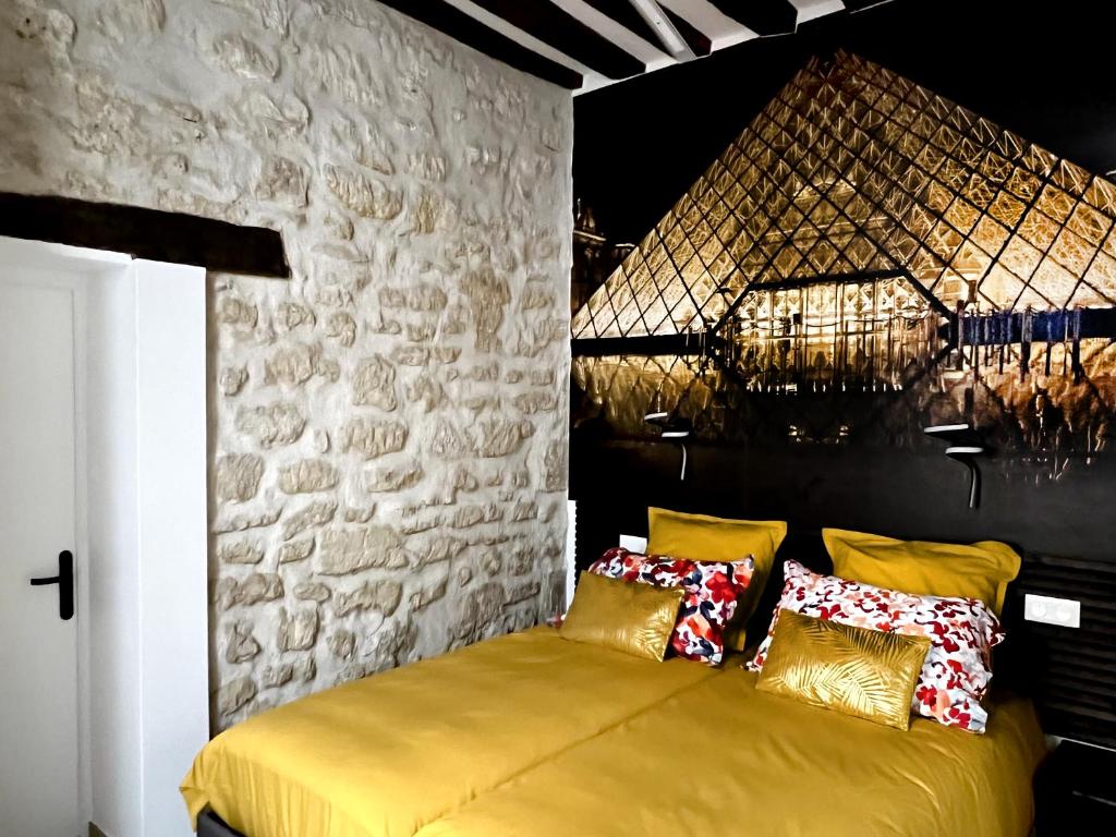 巴黎MARAIS Appartement 2 Chambres 2 Salles de bain - SPA JACUZZI !的一间卧室设有黄色的床和石墙