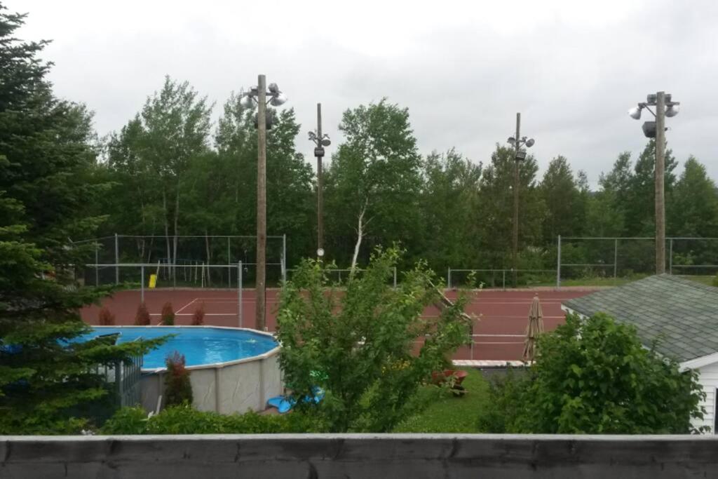 萨格奈Logement avec stationnement tennis et piscine的一个带游泳池的网球场和一个网球场