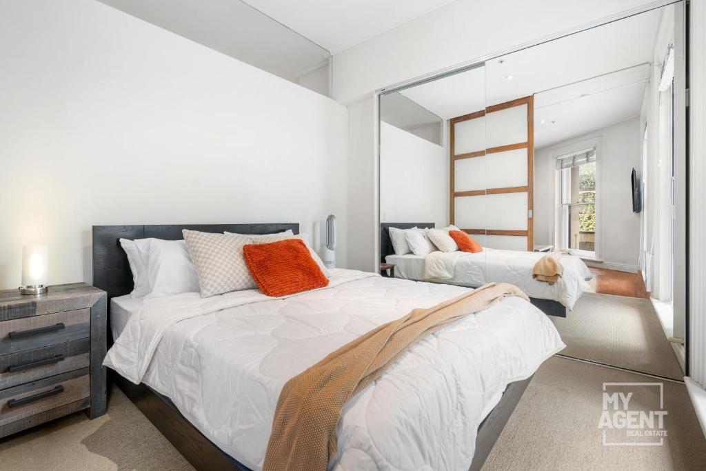 墨尔本Melbourne Bourke Street Bliss的一间卧室配有两张床和镜子