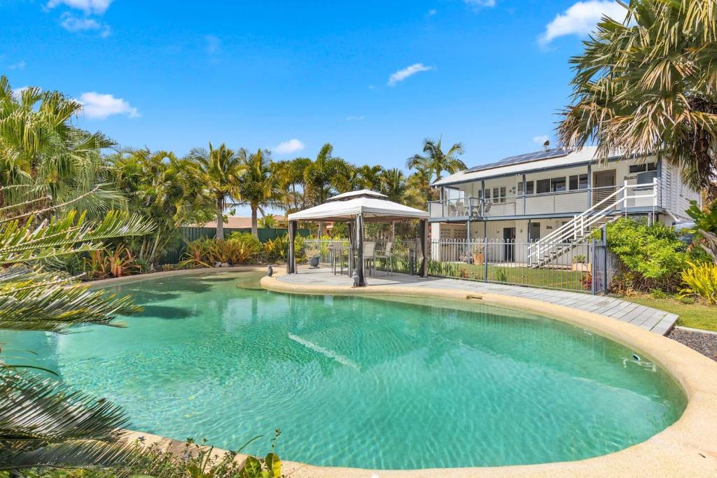 UranganPrivate Resort-style Queenslander at Hervey Bay的房屋前带遮阳伞的游泳池