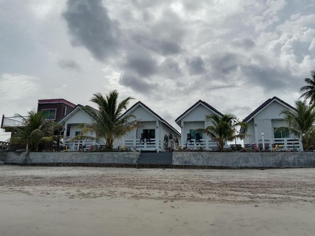 丹绒鲁兰卡威樱草海景酒店的海滩上一排种有棕榈树的房屋