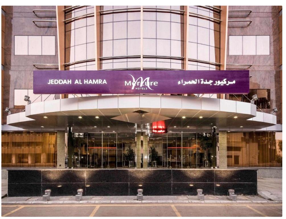 吉达Mercure Jeddah Al Hamraa Hotel的前面有紫色标志的建筑