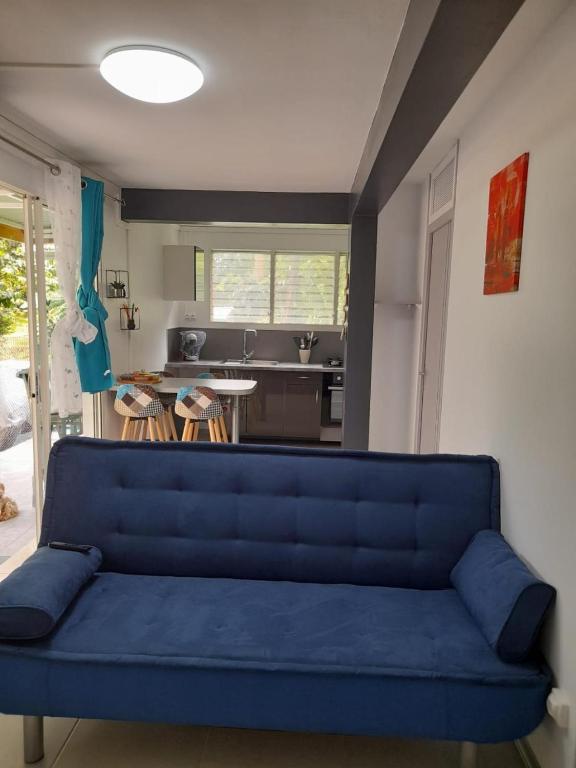 法兰西堡T2 Bambou的客厅设有蓝色沙发,配有厨房