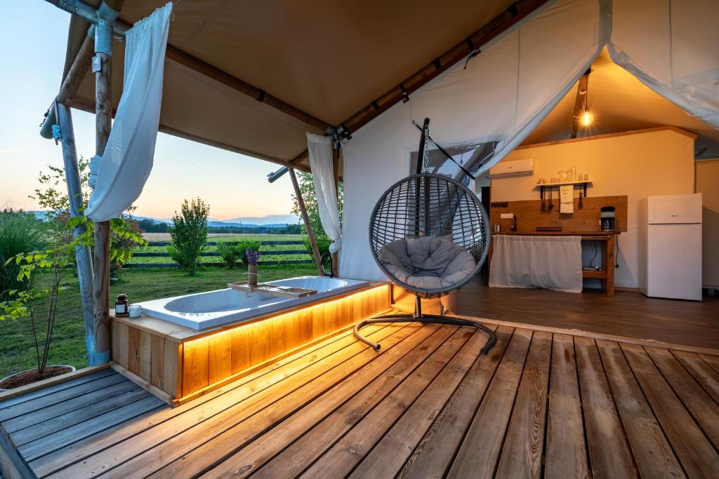 GradacGlamping Kolpa Resort的木甲板上设有浴缸的房间