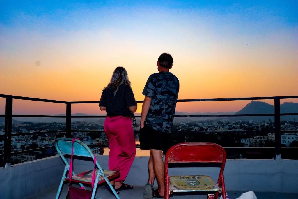 乌代浦Bunkyard Hostel的一对夫妇站在屋顶上欣赏日落