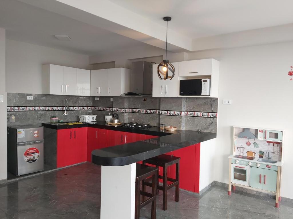 特鲁希略Apartamentos "APPART D'ELIETTE"的厨房配有红色橱柜和黑色台面