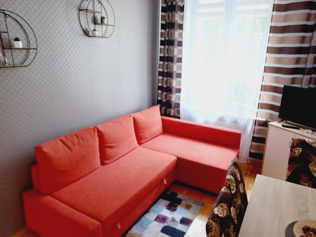 科沙林Apartament ADA的客厅里的一个红色沙发,带有窗户