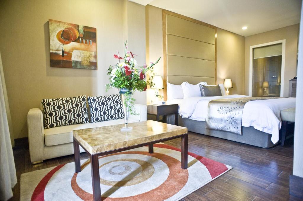 麦克坦Goldberry Suites & Hotel Mactan的酒店客房配有床、桌子和沙发。
