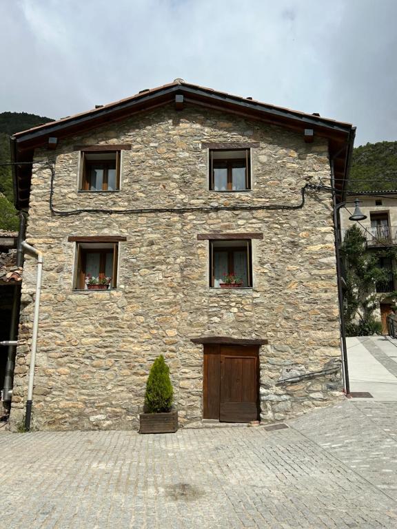 ForcatApartamento Casa Sastre Turismo Rural的一座石头建筑,设有三扇窗户和一扇门