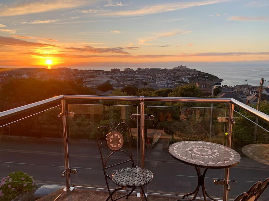 纽基Newquay Sunset & Sea View Apartment in Town Centre的阳台配有两把椅子和一张桌子,享有日落美景。