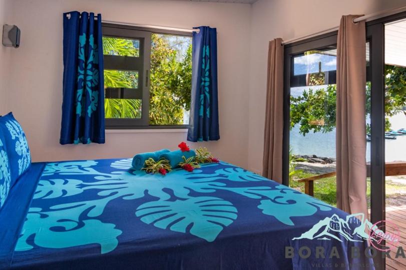 波拉波拉Matira Beach Raitea 2的一间卧室配有一张带鲜花的蓝色床