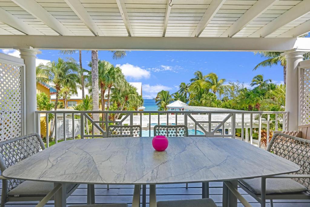 乔治敦Coconut Bay Villas #116的粉红色的球坐在门廊的桌子上