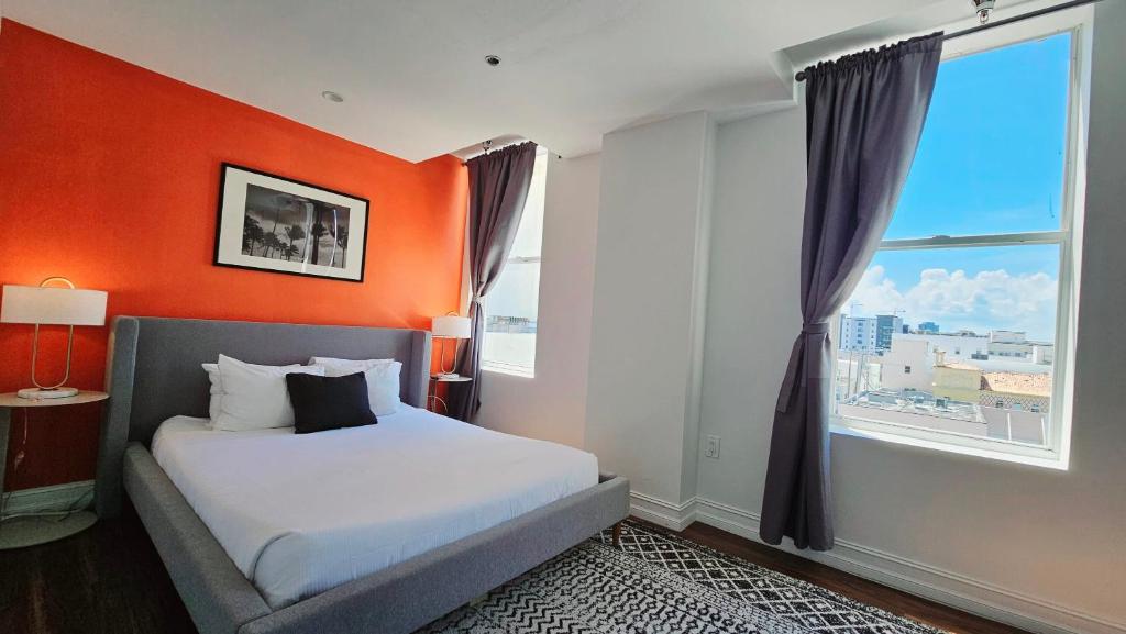 西棕榈滩The Lofts on Clematis 407 Downtown West Palm Beach的一间卧室设有橙色墙壁、一张床和一个窗户