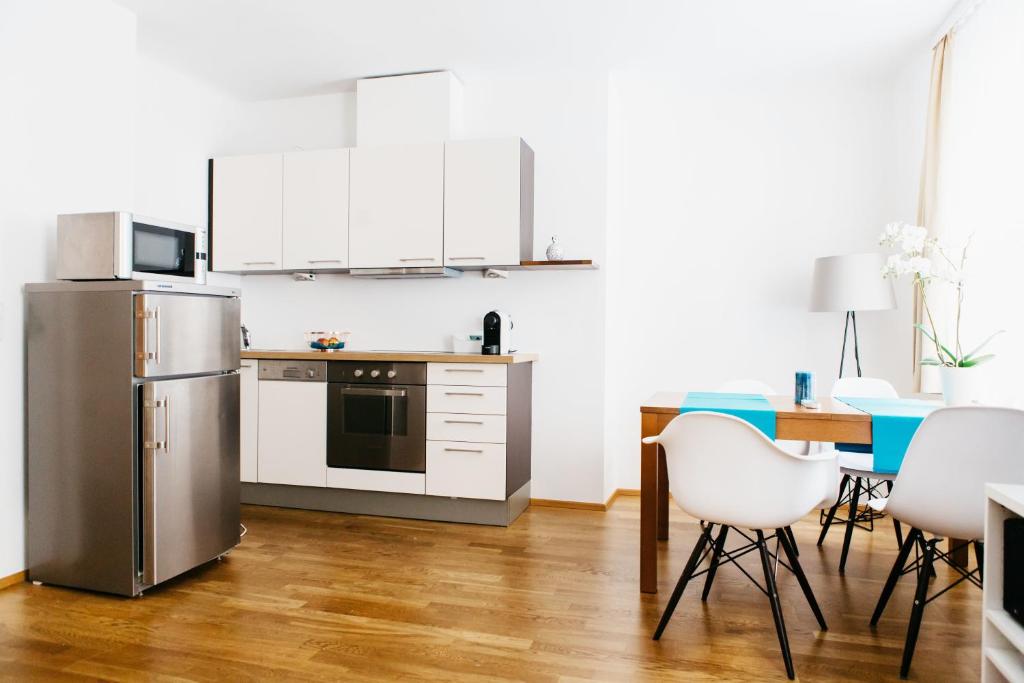 维也纳Home Sweet Apartments | contactless check-in的厨房配有白色橱柜和桌椅