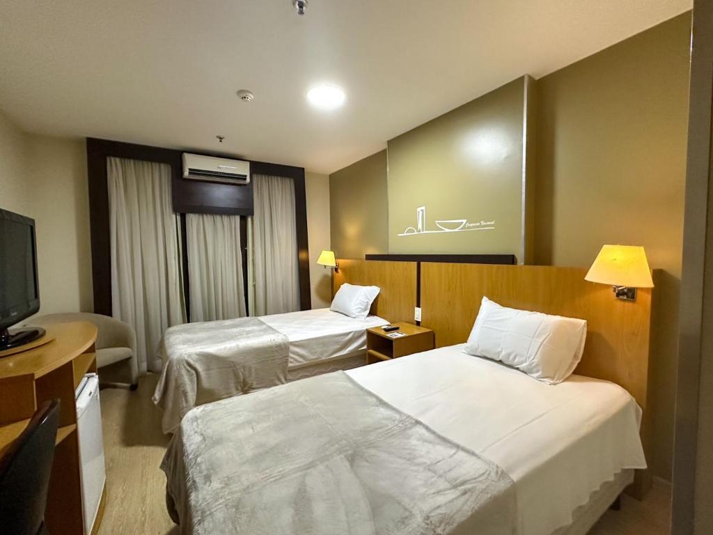 塔瓜汀加Flat 213 - Comfort Hotel Taguatinga的酒店客房设有两张床和一台平面电视。