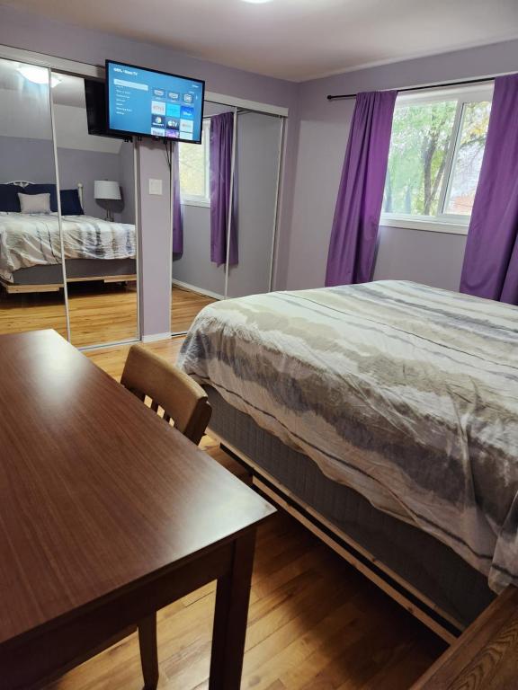 温尼伯Winnipeg Place to Stay的一间卧室配有一张床、一张桌子和一台电视。