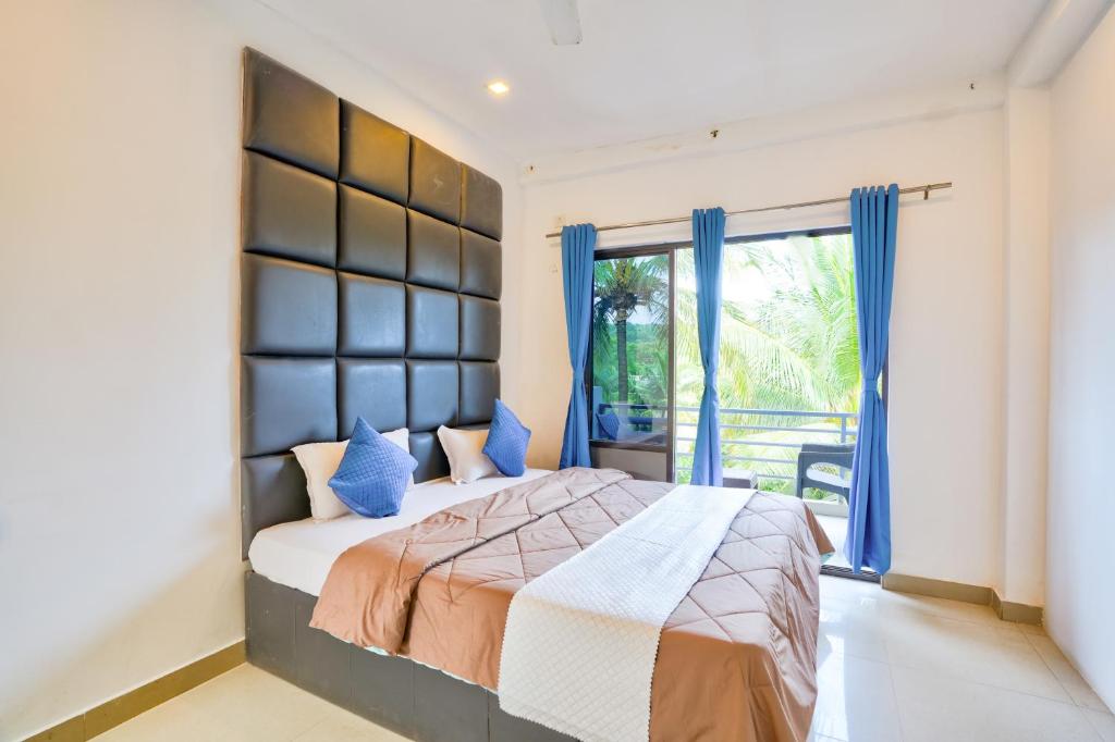 坎多林GOA Down D Vilage Prime的一间卧室配有一张带蓝色窗帘的床和一扇窗户