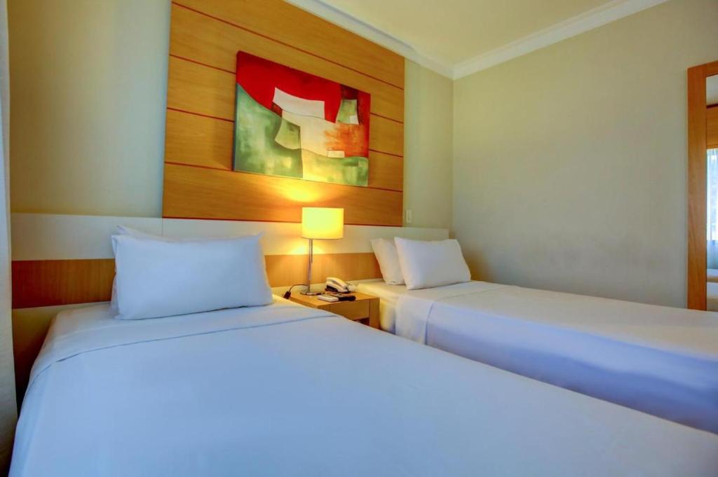 圣保罗Suite Congonhas - FLAT Aeroporto Congonhas的一间卧室配有两张床、一盏灯和一幅画