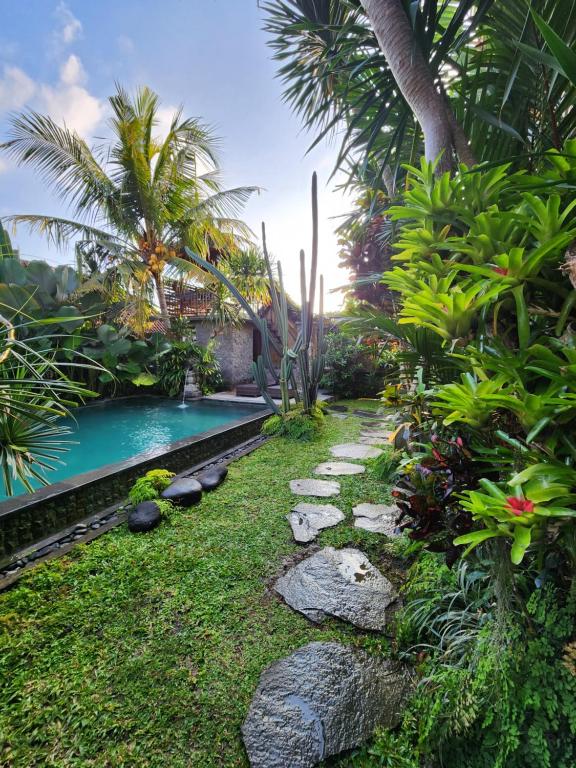 乌布BUDA AMITABA的一个带游泳池和棕榈树的花园