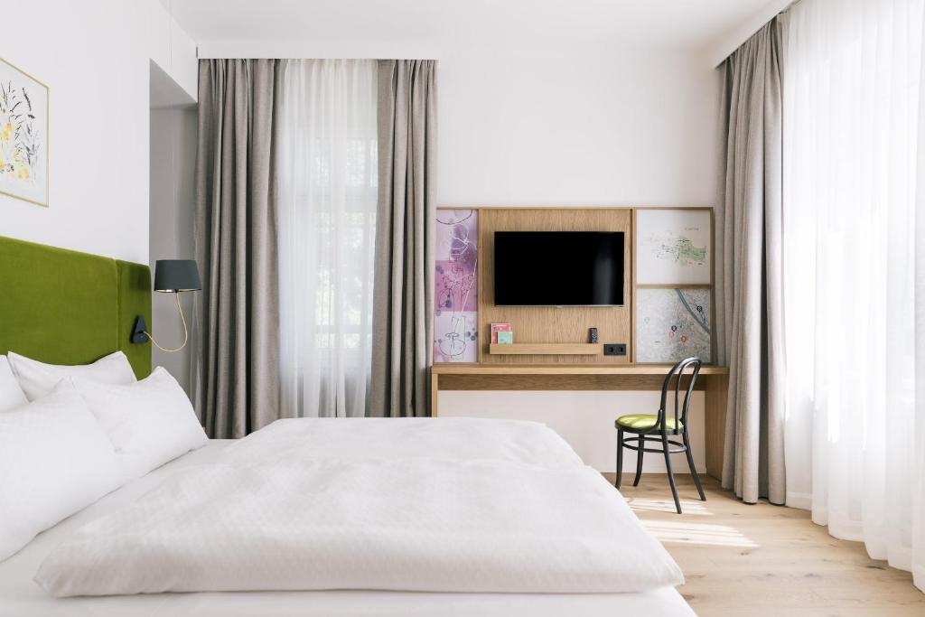 维也纳Bio-Hotel Schani Wienblick的一间卧室配有一张床和一张书桌及电视