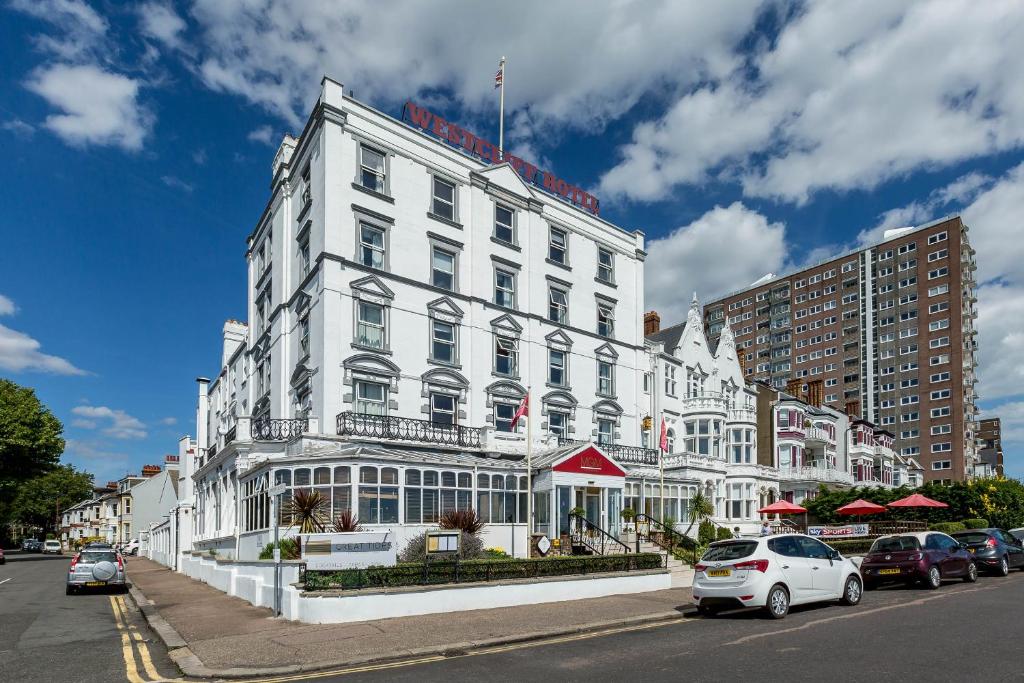 滨海绍森德Muthu Westcliff Hotel (Near London Southend Airport)的一座白色的建筑,前面有汽车停放