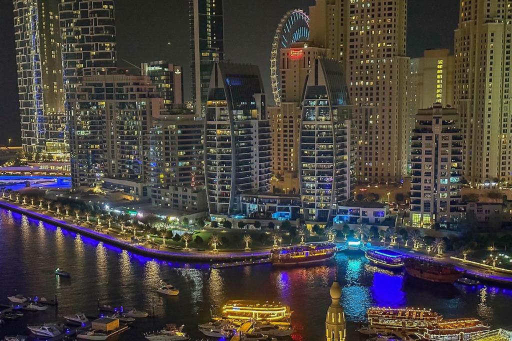 迪拜Marina Yacht Club Views - 3BR Modern Furnished的城市天际线,夜晚在水中划船