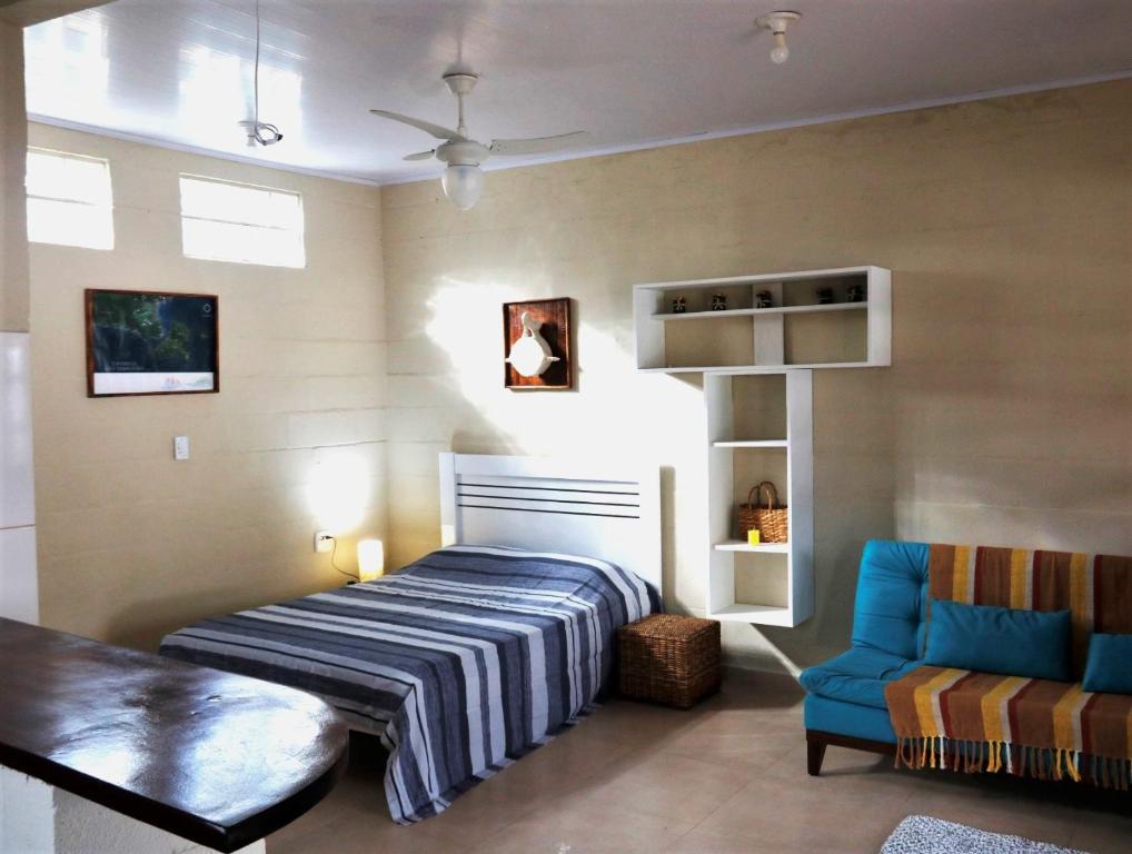 圣塞巴斯蒂安Rancho do Capitão Boiçucanga的一间卧室配有一张床和一张蓝色椅子