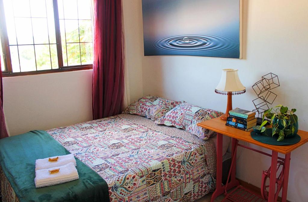 德班Cosy Boho Cottage - All to Yourself!的一间卧室配有一张床和一张带台灯的桌子