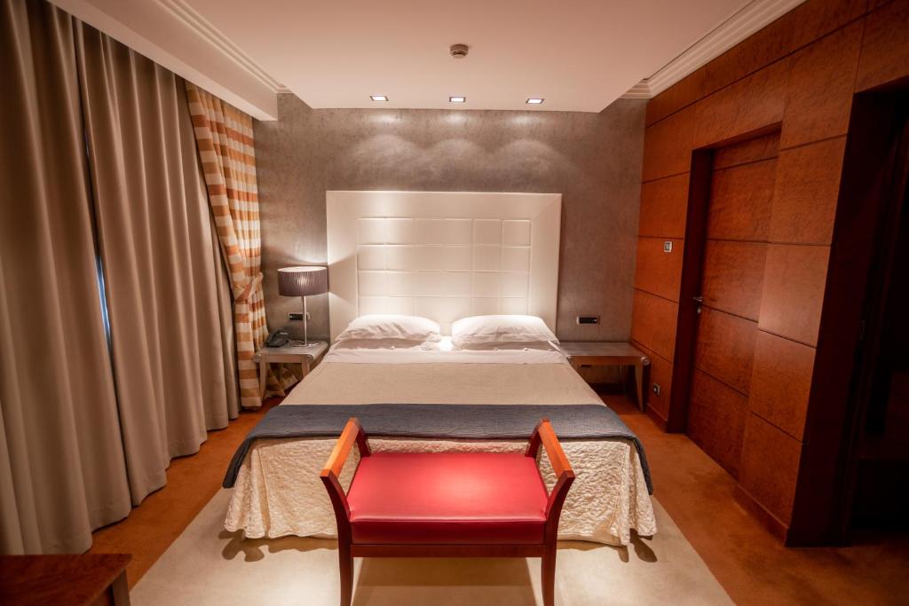 罗马罗马帕皮洛度假酒店的一间卧室配有一张床和一张红色椅子