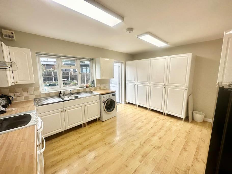 Erith5 Bedroom house in DA7的厨房铺有木地板,配有白色橱柜。