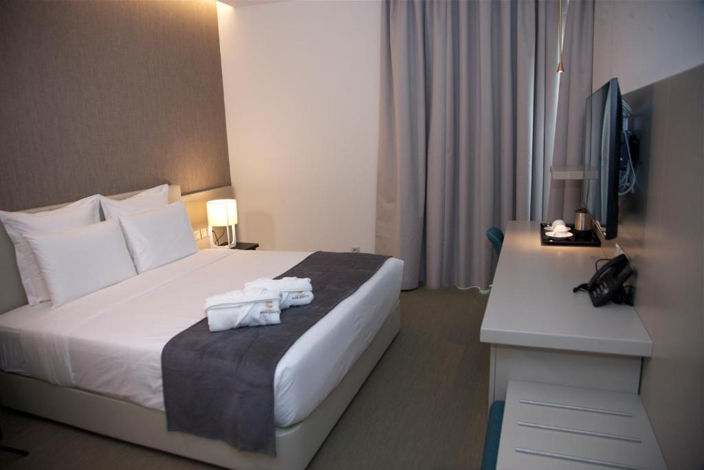 罗安达Hotel Continental Horizonte的酒店客房配有一张床和一张书桌及一台电视