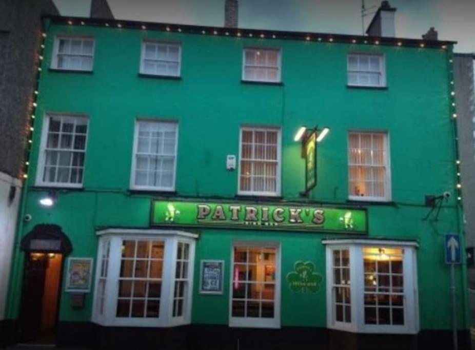 班戈Patrick's Bar的一座绿色建筑,前面有标志