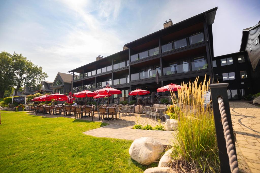 NisswaQuarterdeck Resort的配有桌椅和红色遮阳伞的酒店