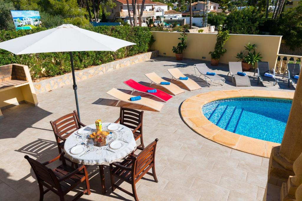 莫莱拉Villa Llobell - Plusholidays的游泳池旁配有桌椅和遮阳伞