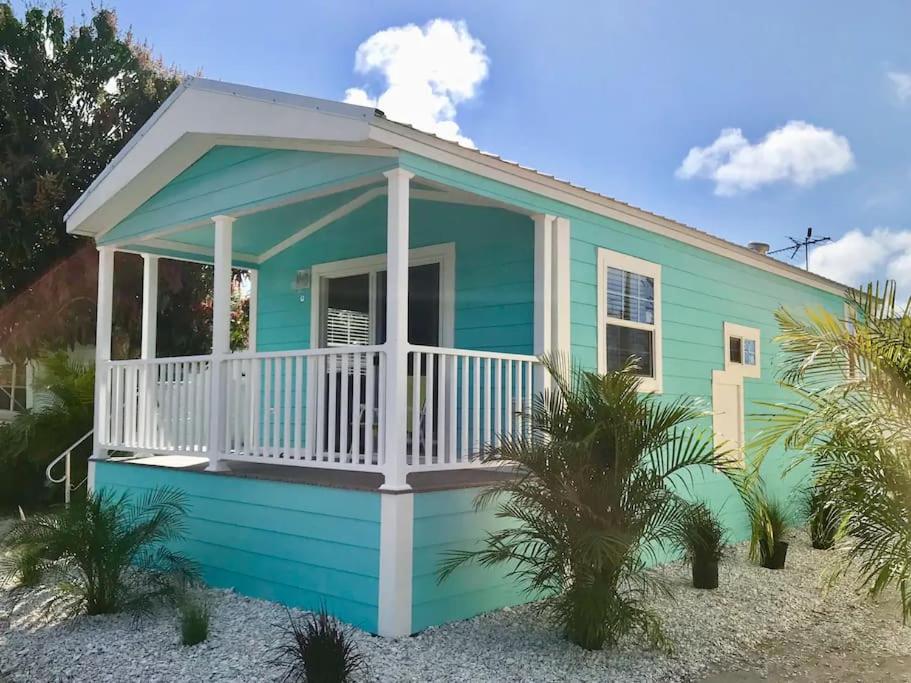 萨拉索塔Pinecraft Blue Heron Tiny Home的海滩上带白色门廊的蓝色房屋