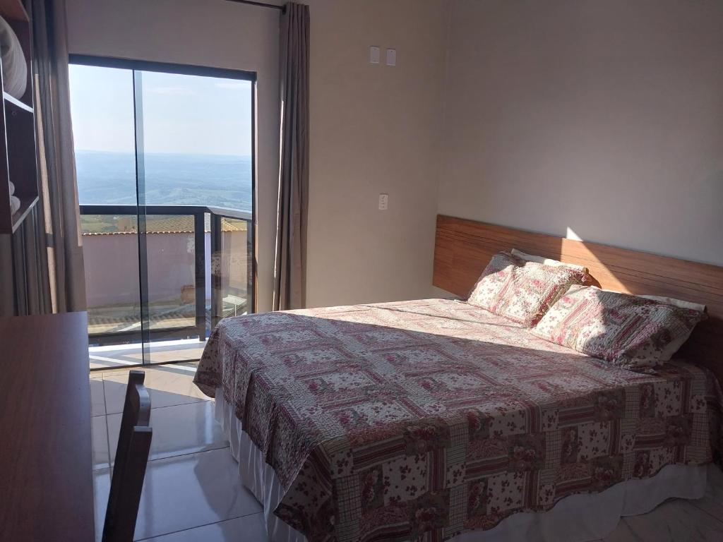 圣托梅-达斯莱特拉斯Hotel-Pousada Quartzo Rosa的一间卧室设有一张床和一个大窗户