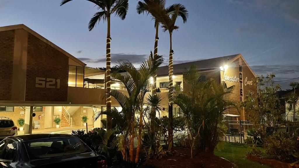 布里斯班兰开斯特科特汽车旅馆的棕榈树建筑前的停车场