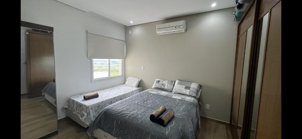 瓜拉廷格塔Quartos privativos - Casa de alto padrão的一间卧室设有两张床和窗户。