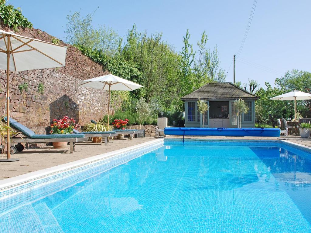 佩恩顿庞德之家乡村别墅的一个带遮阳伞的游泳池和一个房子